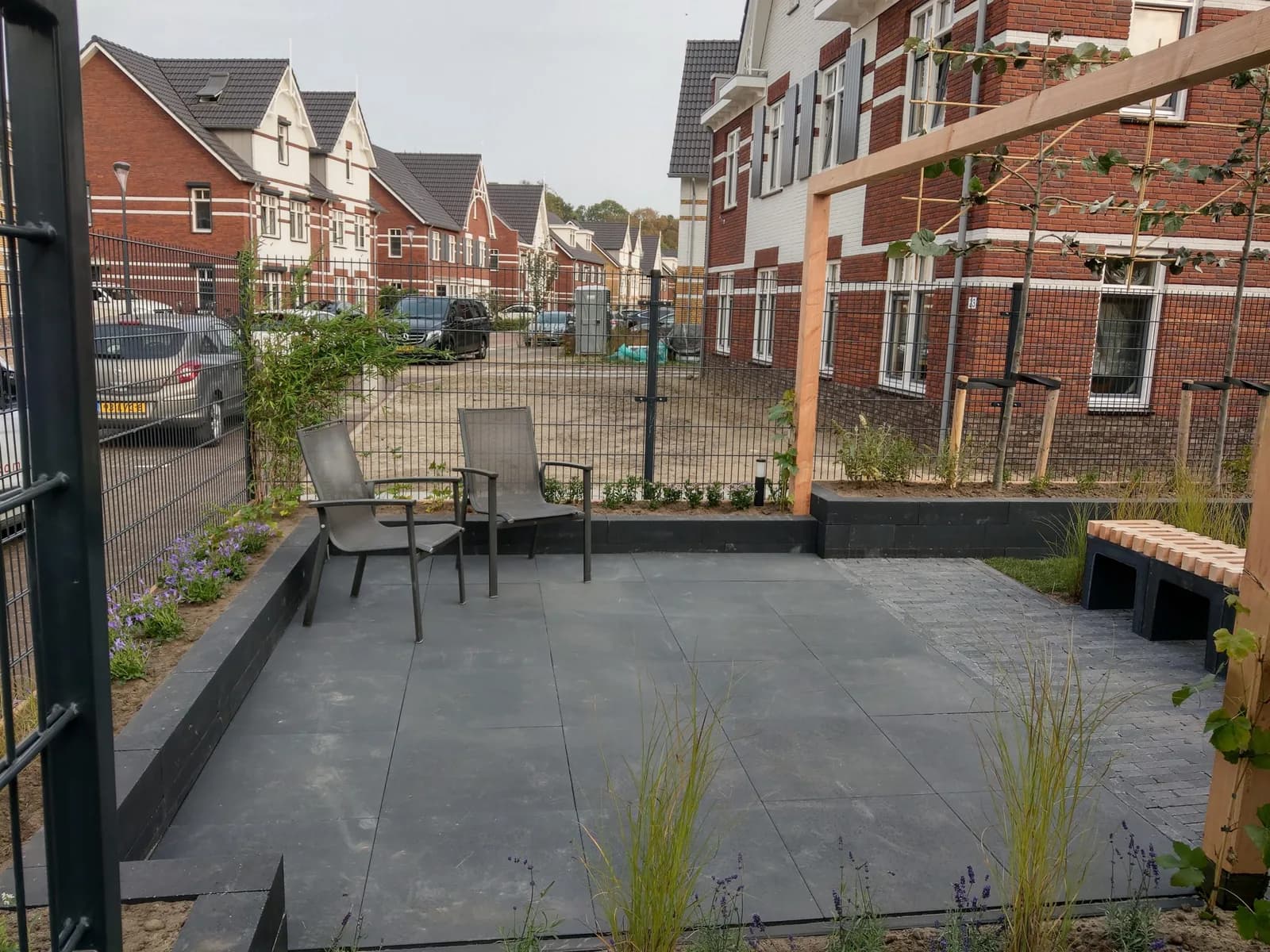 Stadstuin met groot tegelterras, verhoogde borders en een houten pergola